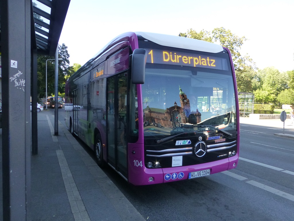 Mercedes E-Bus Wiesbaden mit Bahnhofsgebude.jpg